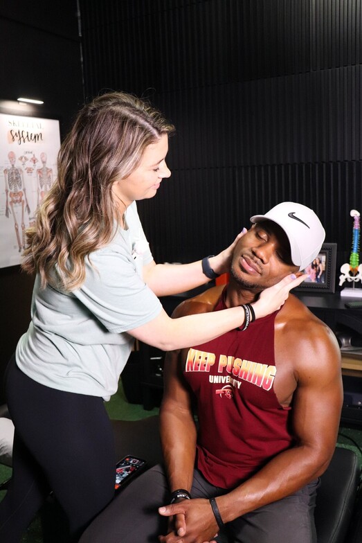 Chiropractor performing a cervical spine adjustment on a male athlete seated in the treatment room at Limitless Sports Chiropractic in Oak Point, TX