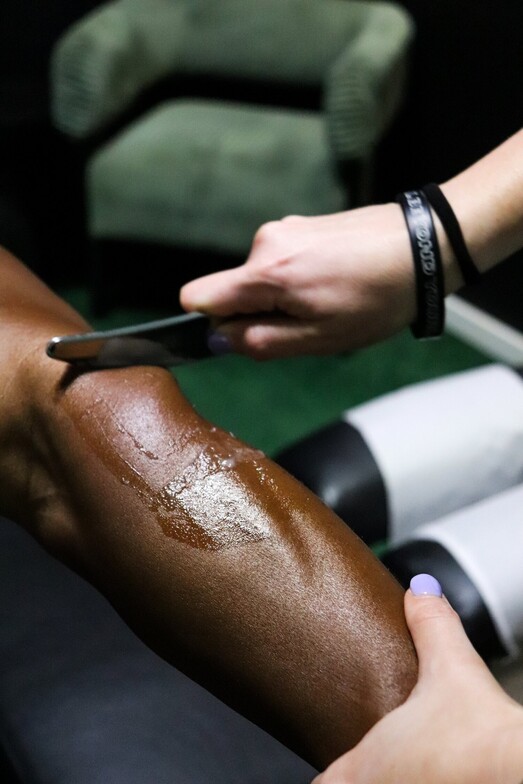 Graston Technique instrument being used to treat calf muscle tightness on an athlete's lower leg.