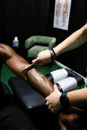 Graston Technique instrument-assisted soft tissue treatment applied to a patient's lower leg, the same manual therapy approach used to treat scar tissue and chronic instability after an ankle sprain at Limitless Sports Chiropractic.