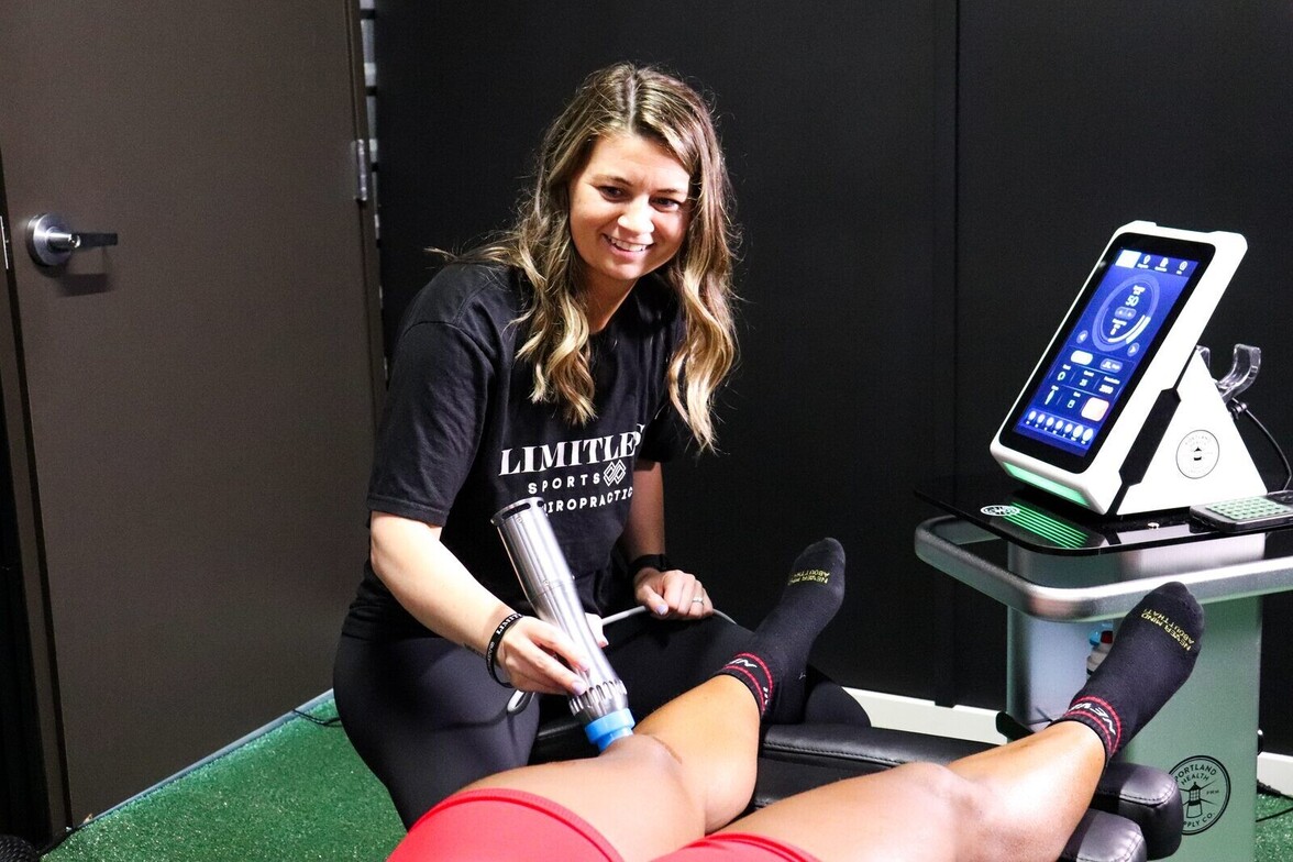 Shockwave therapy device being applied to a patient's lower leg, the same treatment approach used to treat prepatellar knee bursitis at Limitless Sports Chiropractic.