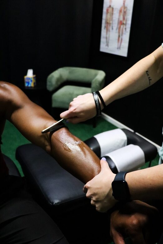 Graston Technique instrument-assisted soft tissue treatment applied to a patient's lower leg, the same manual therapy approach used to treat scar tissue and chronic instability after an ankle sprain at Limitless Sports Chiropractic.