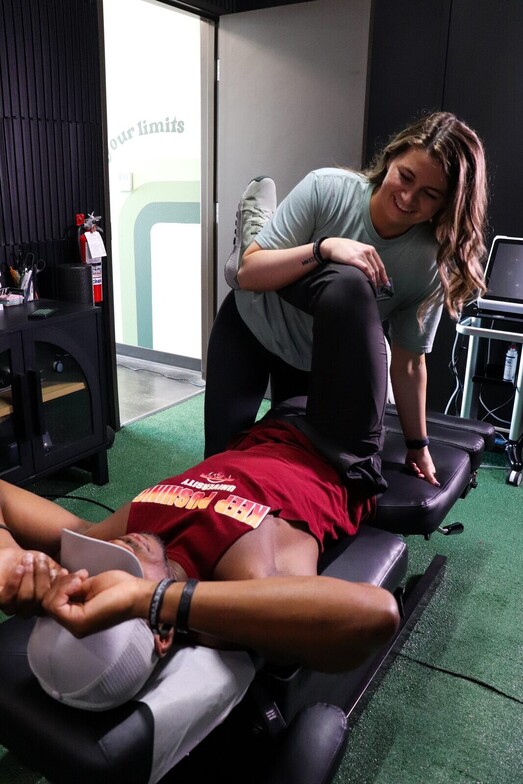 Manual straight-leg hamstring stretch being performed on a patient at Limitless Sports Chiropractic, illustrating myofascial release treatment for hamstring tightness.
