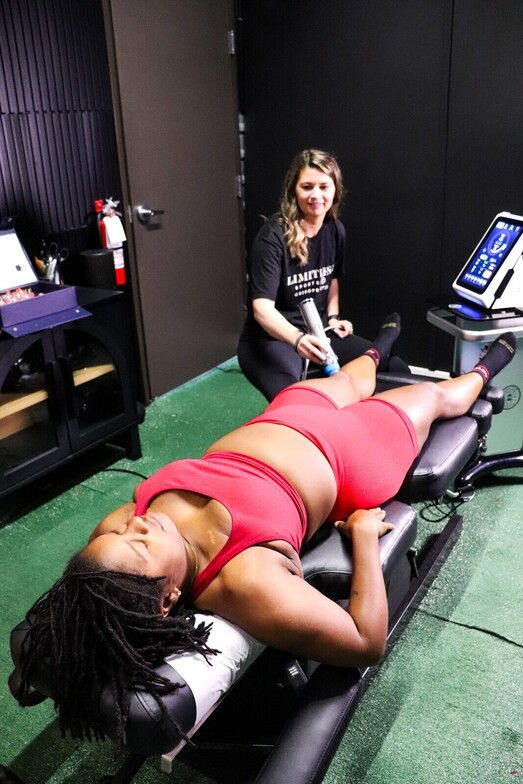 Shockwave therapy device being applied to a patient's upper leg to treat proximal hamstring tendinopathy at Limitless Sports Chiropractic